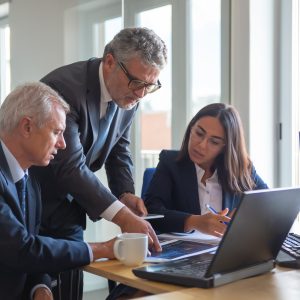 Concentrated colleagues watching statistic charts and talking about work. Professional senior managers and young assistant preparing business plan. Teamwork, management and partnership concept